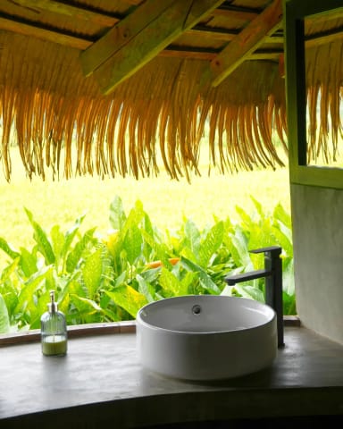 Salle de bain extérieure avec double vasque et vue sur la nature.